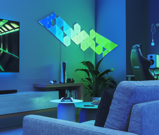 This is an image of Nanoleaf Shapes light panels in a living room beside a TV. The layout is composed of all 3 shapes in the Nanoleaf Shapes line. The RGB light panels are connected with each other using linkers and create a design that bends around the corner using flex linkers. The perfect living room lights for entertaining and watching movies.