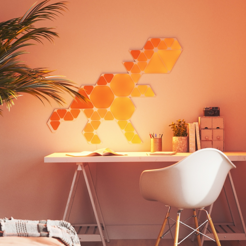 Nanoleaf Shapes Thread-enabled color-changing mini triangle smart modular light panels mounted to a wall above a desk. Similar to Philips Hue, Lifx. HomeKit, Google Assistant, Amazon Alexa, IFTTT.